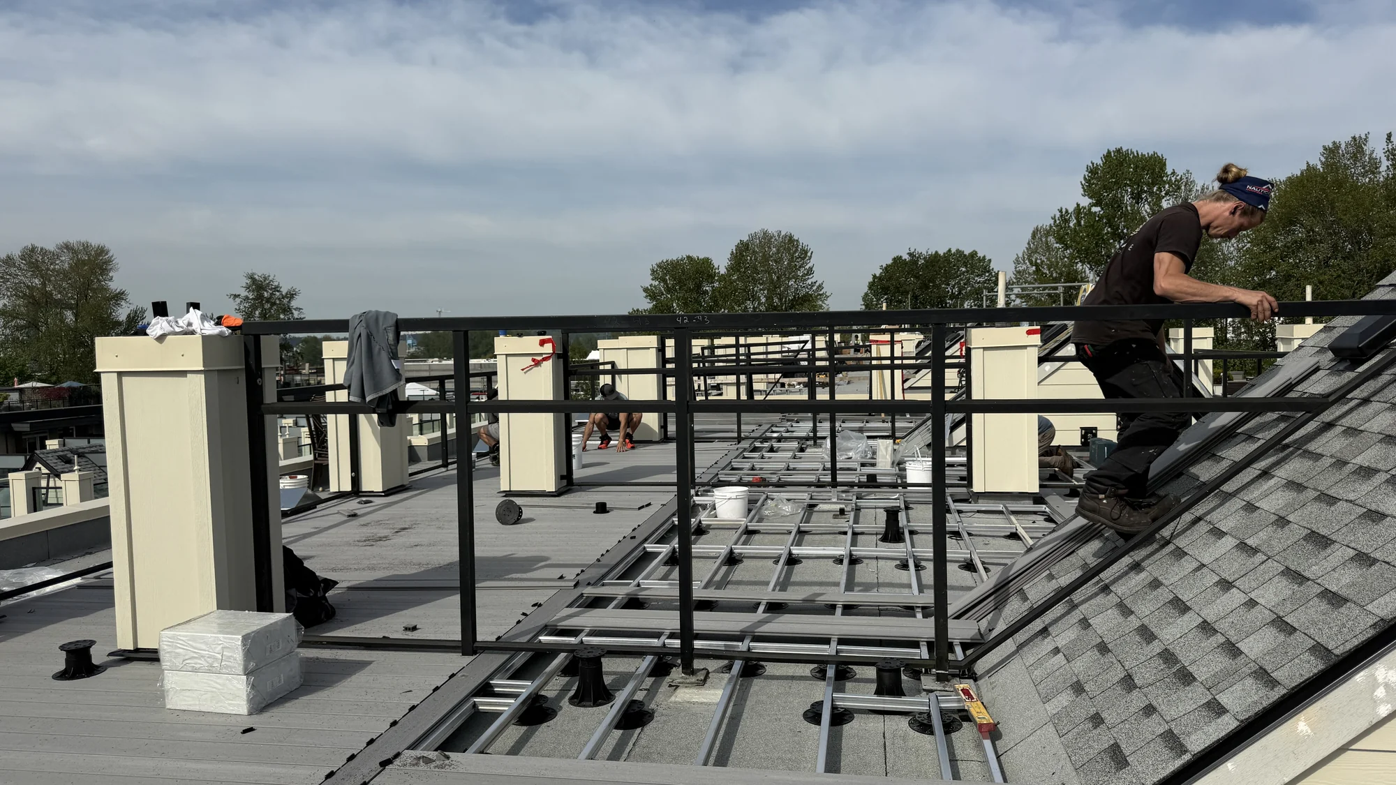 Installers working on NOMA rooftop decking beside the modular aluminum joist and pedestal framework