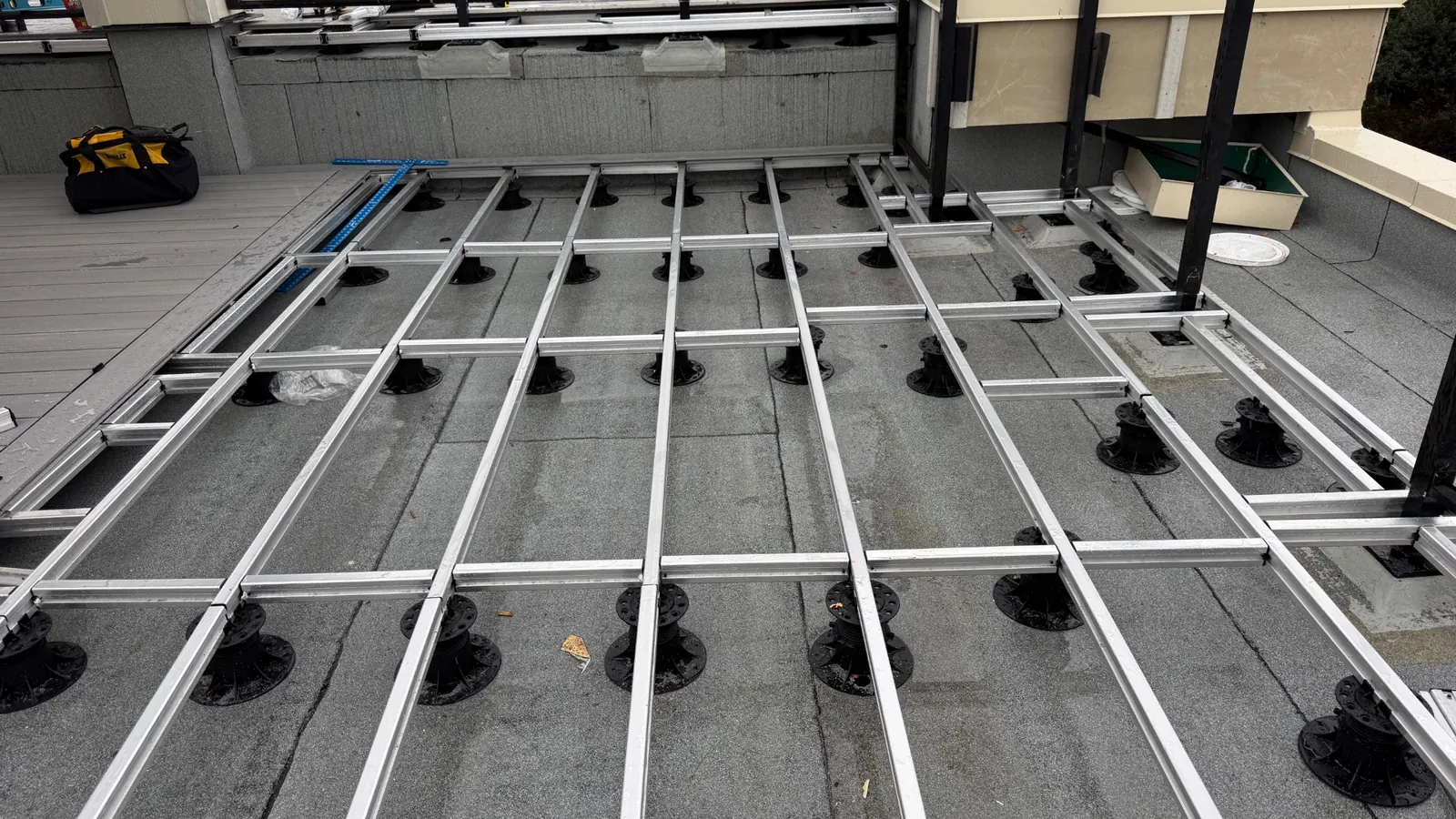 NeoLine aluminum joists supported by adjustable pedestals during a rooftop deck installation
