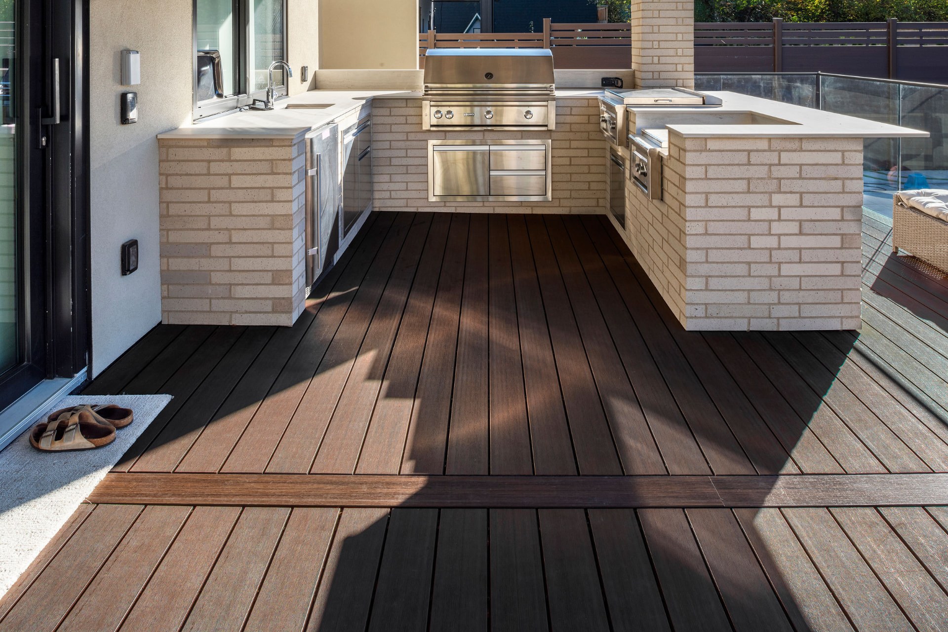 The regular decking surface beneath the outdoor kitchen.