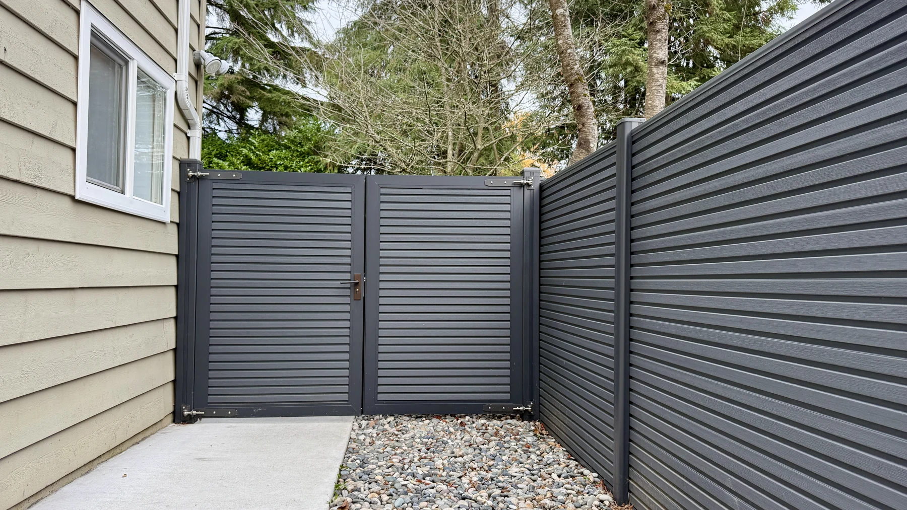 A Graphite NeoLine double swing gate with two leaves and matching composite fencing