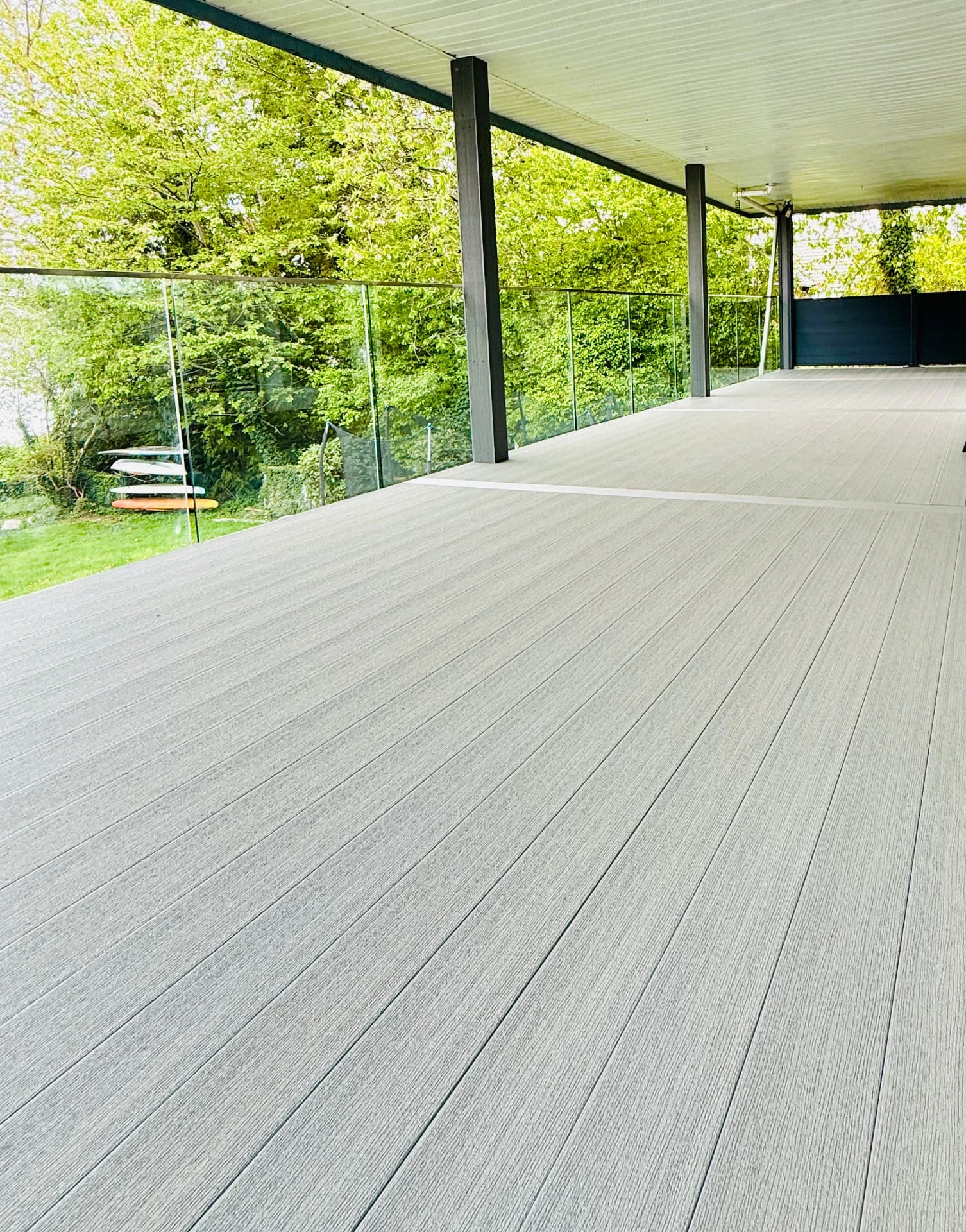 The decking surface along the glass railing.
