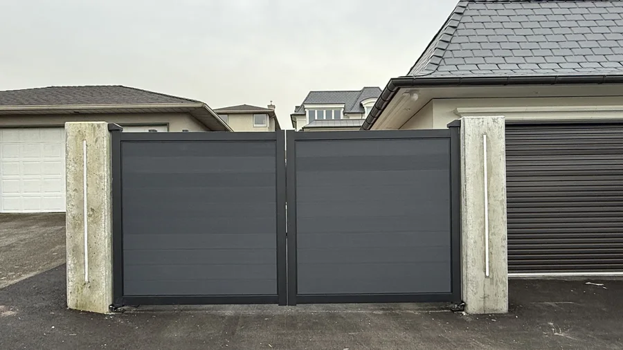 Graphite electric double swing driveway gate between concrete pillars